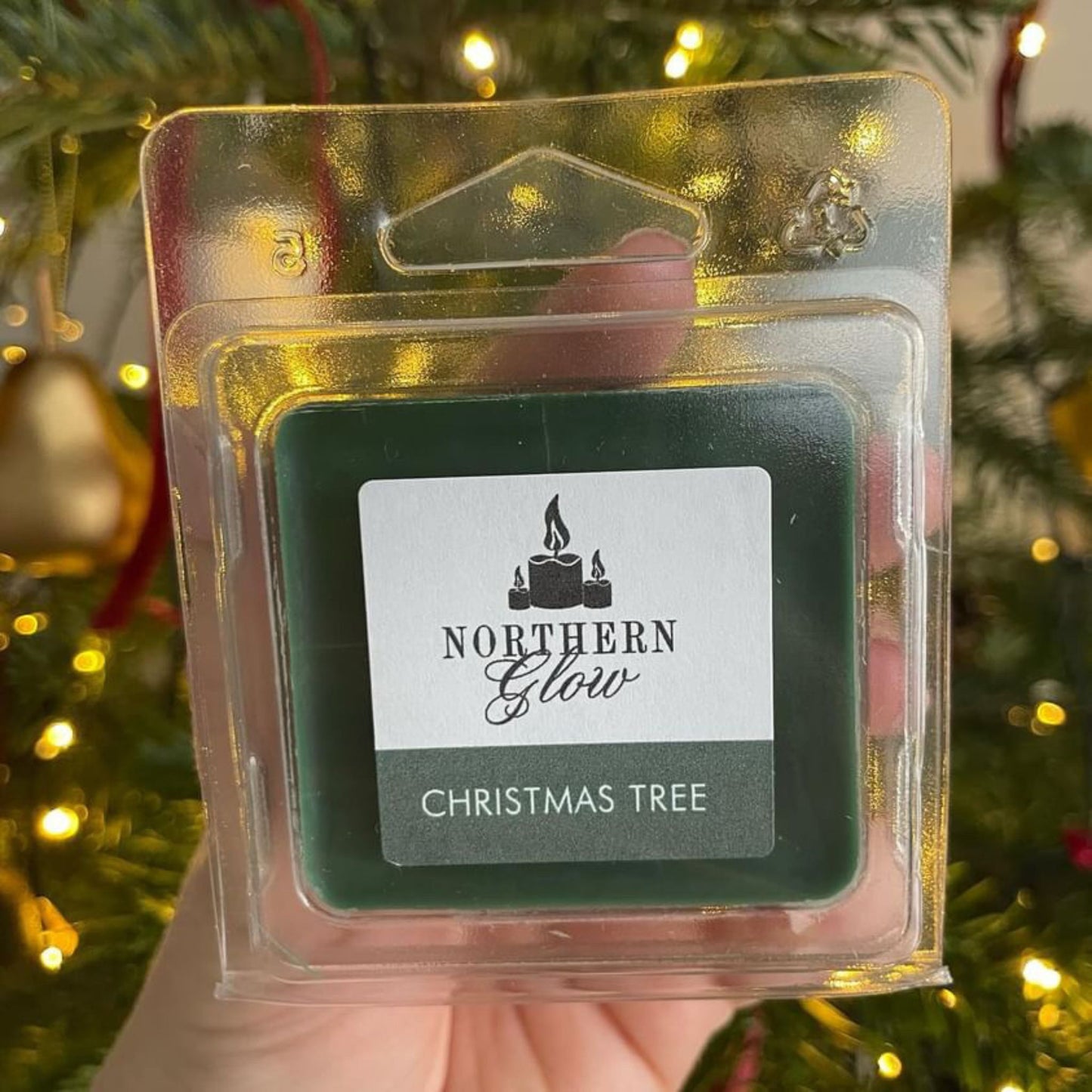 Christmas Tree wax melt is a green colour in a plastic case. The melt has four individual cubes to split. The label is white with the logo in the centre. 'Christmas Tree' is in white writing with a green background.