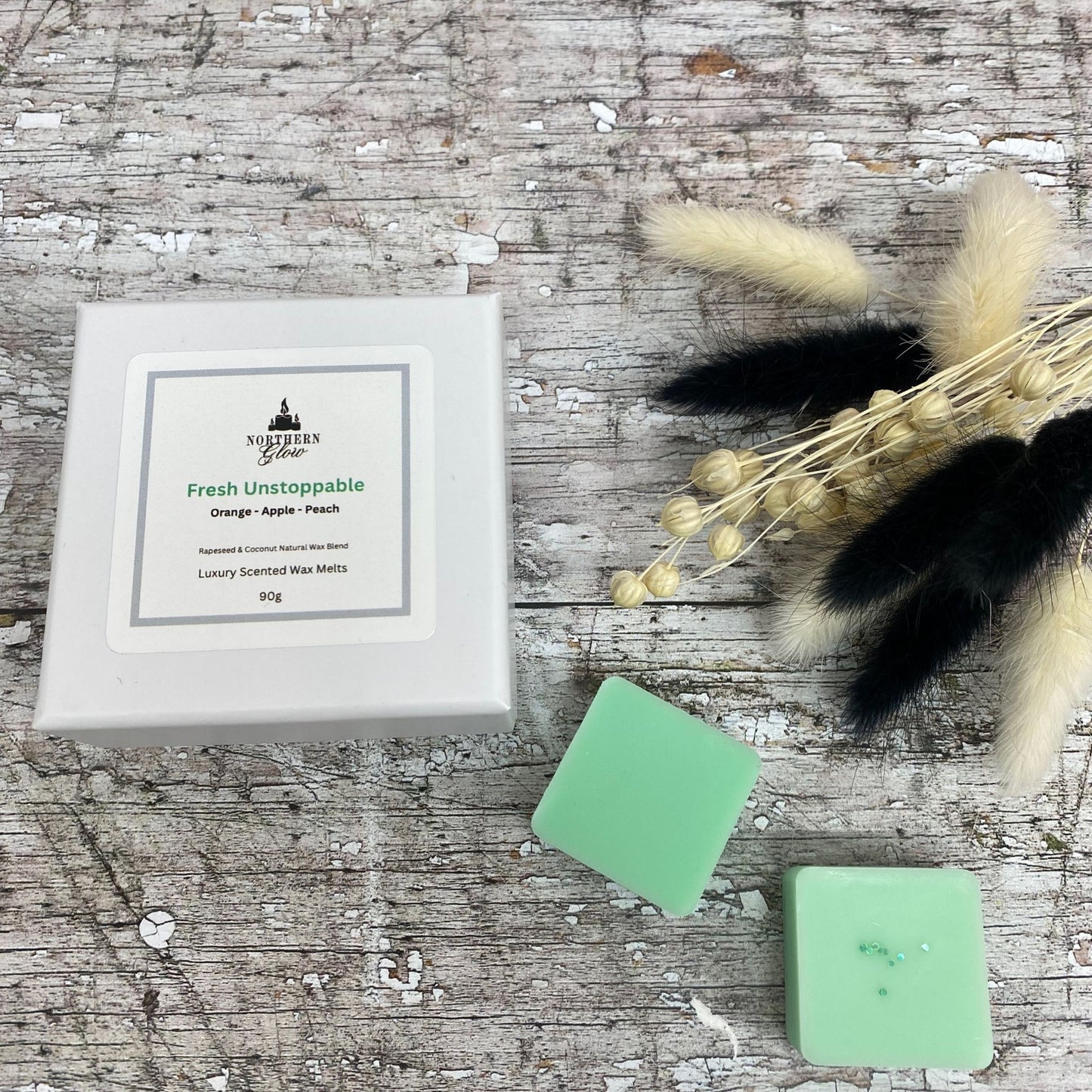 Fresh Unstoppable wax melt is a green colour and each melt is a square shape in a white box. There are eight individual wax melts in the white box. The label is white with a silver border. The logo is at the top with 'Fresh Unstoppable' in green writing, in the centre.