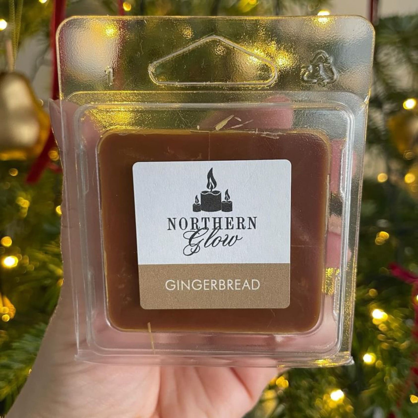 Gingerbread wax melt is a brown colour in a square shape with four individual cubes. It is in a plastic case with a white label on the front with the logo in the centre. 'Gingerbread' is in white writing with a brown background and the bottom of the label.