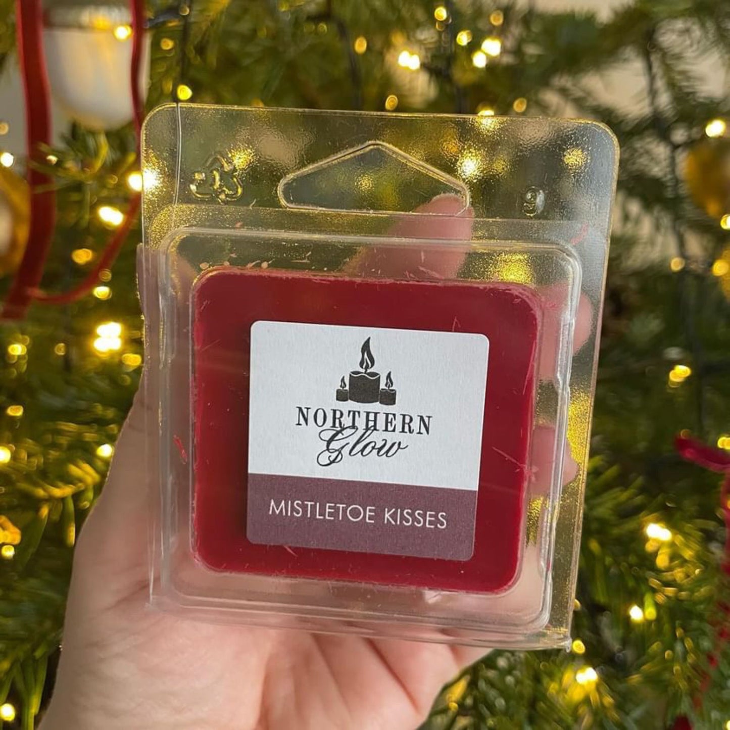 Mistletoe Kisses is a red colour in a plastic case. The melt has four individual cubes that can be split. The label is in white with the logo in the centre. 'Mistletoe Kisses' is in white writing in a red background.