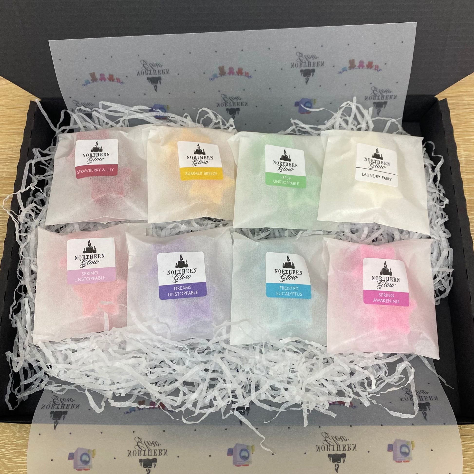 Clean and fresh sample box is in a black box with all eight fragrances inside. Each melt has two stars in the glassine bag, they are wrapped in a clean design paper